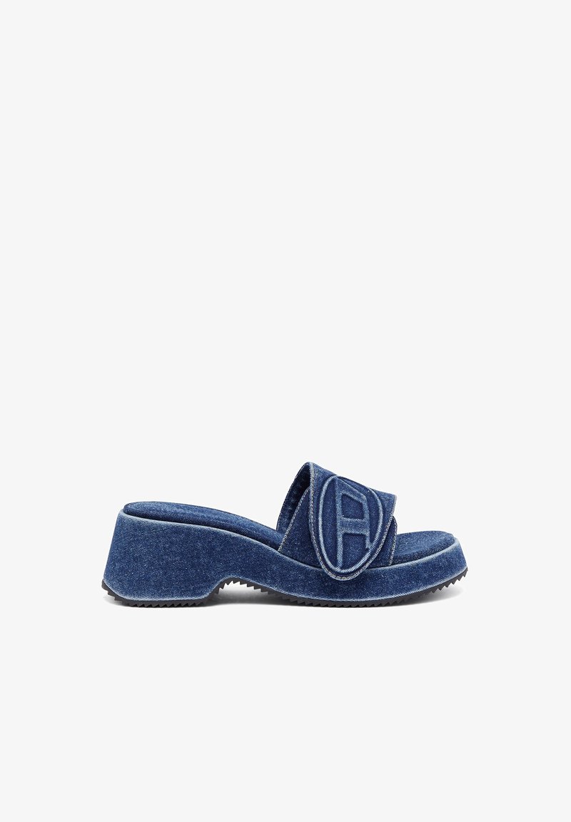 Denim glid sandal med en tykk plattform, med en avrundet tå og en stor logo detalj på stroppen. Blåfarge med kontraststing.