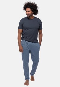 Dunkelgraues T-Shirt mit kurzen Ärmeln, kombiniert mit hellblauen gemusterten Jogginghosen, die über einen elastischen Bund und eine lockere Passform verfügen.