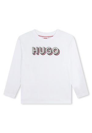 T-shirt blanc à manches longues avec un col rond, arborant un design graphique "HUGO" multicolore en lettres grasses sur le devant.