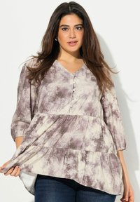 Una blusa fluida a più strati in grigio tenue e crema con scollatura a V e bottoni frontali. Presenta maniche a tre quarti e una morbida texture del tessuto.