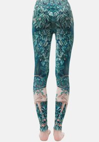 Leggings met een gedetailleerd loofpatroon in groene tinten, met crèmekleurige accenten en artistieke bos elementen. Stretch stof afwerking.