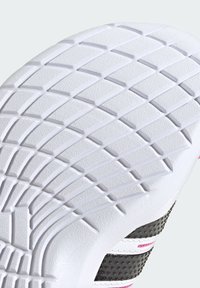 La semelle de la chaussure présente une surface en caoutchouc blanc texturé avec un motif en zigzag, agrémentée d'éléments gris et roses sur le côté de la chaussure.