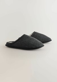Zapatillas de tela grises con un patrón texturizado, punta redonda, forro suave y una suela flexible de goma negra. Diseñadas para uso en interiores.