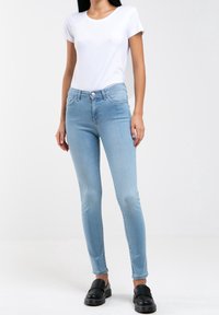 Ljusblå skinny jeans i denim, med en medelhög midja, fem fickor och knappstängning. Matchas med en vit t-shirt.