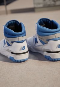 Sneaker alte in pelle bianca con accenti blu e grigi. Materiale textured, collo imbottito e logo sul tallone.
