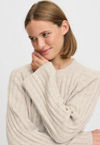 Hellbeige gerippter Strickpullover mit Rundhalsausschnitt und weiten Ärmeln, der eine weiche Textur und einen lässigen Schnitt aufweist.