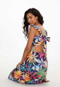 Květinové maxi šaty v námořnické modři, s barevnými tropickými vzory, volánkovými ramínky a otevřeným designem zad se stužkou.