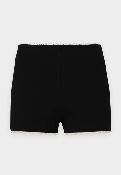 Shorts noirs ajustés avec une texture côtelée subtile et une bordure en dentelle blanche le long de la taille et des ouvertures pour les jambes.