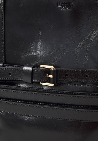 Black leather handbag featuring a smooth texture, gold hardware buckle, and stitch detailing. Logo embossed at the top center.