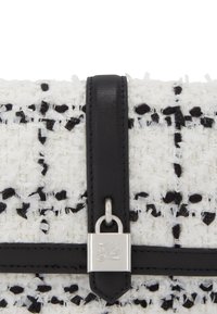 Clutch din tweed alb-negru cu o finisare texturată, dotat cu o curea din piele neagră și un închizător din metal argintiu.