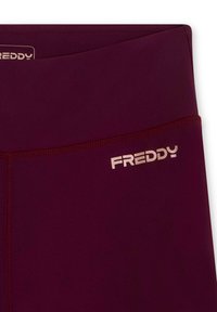 Leggings bordeaux con una texture liscia. La cintura presenta un sottile logo dorato "FREDDY" sul lato sinistro. Le cuciture sono pulite e minimali.