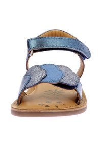 Sandalia de cuero azul con una correa ancha y un diseño festoneado en tonos de azul variados, una plantilla de color marrón claro y una suela plana.