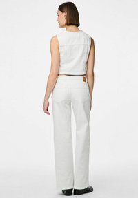 Balts īsais denima tops ar noapaļotu kakla izgriezumu, kombinēts ar augsto vidukli un platu kāju baltām džinsām. Gluda tekstūra un minimālistisks dizains.