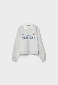 Sweat-shirt à manches longues gris clair avec col blanc, imprimé "NEW YORK" en bleu marine, écriture "Manhattan" et petit drapeau américain sur le devant.