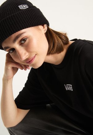 Zwarte gebreide beanie met een wit Vans-logo; model draagt een zwart t-shirt met ronde hals met hetzelfde logo in het wit; gladde huid en kort haar.