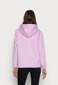 Pullover-Hoodie in Hellpink, gefertigt aus weichem Stoff, mit einer Kordelzugkapuze und gerippten Bündchen, locker geschnitten und mit seitlichen Schlitzen am Saum.