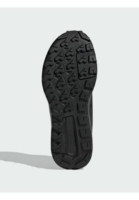 Semelle en caoutchouc noir avec un motif texturé, présentant des motifs angulaires et de profondes rainures pour une adhérence optimale. Conçu pour la stabilité et la durabilité.