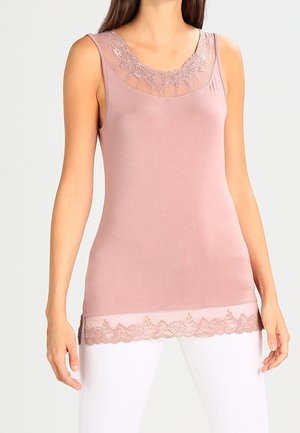 Top sin mangas de color rosa polvoriento con ribete de encaje en el escote y el dobladillo, combinado con pantalones blancos.