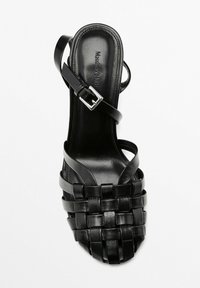 Sandalo alto in pelle nera con design a tracolla intrecciata, punta aperta, cinturino alla caviglia con fibbia, texture liscia e soletta marchiata.