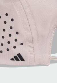 Tissu rose clair avec une finition texturée, orné de points noirs et d'un logo Adidas noir en bas à gauche.