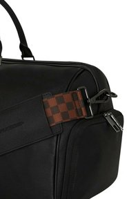 Bolso de cuero negro con un acabado texturizado, una correa a cuadros marrón, herrajes metálicos y un detalle de bolsillo con cremallera.