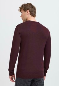 Burgunderfarget genser med lange ermer og rund hals, med ribbestrikkede mansjetter og nederkant, laget av mykt, strukturert strikket stoff. Enkel, klassisk design.