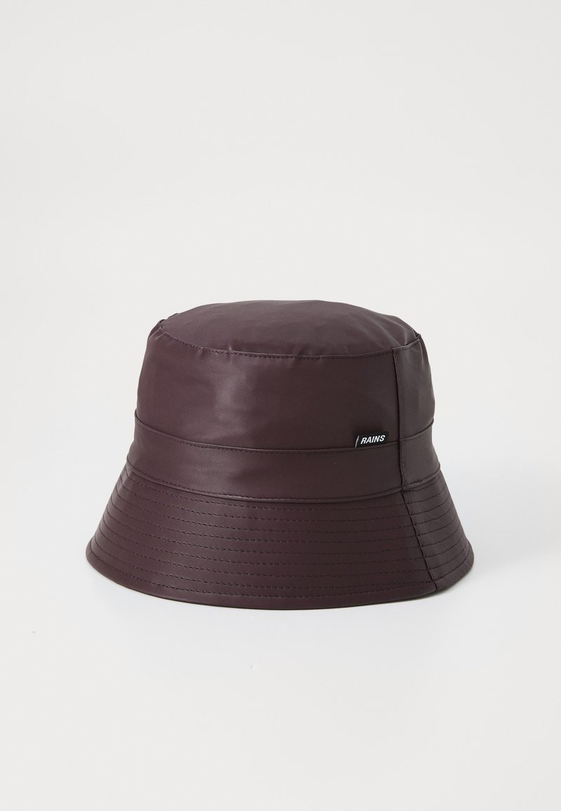 Cappellino a secchiello di colore marrone scuro, realizzato in materiale impermeabile. Presenta una visiera a coste e un piccolo etichetta con logo sul lato. Texture liscia nel complesso.