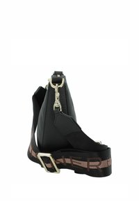 Bolso de cuero negro con una textura distintiva, forma triangular y herrajes plateados. Presenta una correa con un patrón en negro y marrón.