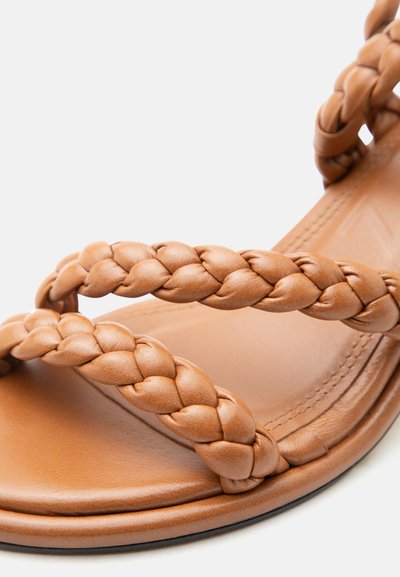 Δερμάτινο σανδάλι ταμπά με δύο πλεγμένα λουριά πάνω από το πόδι και εμφανή ράμματα στη σόλα.