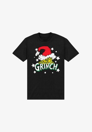 Camiseta negra con un gráfico verde del Grinch que lleva un sombrero de Santa rojo, el texto "GRINCH" y estrellas blancas como acentos de diseño.
