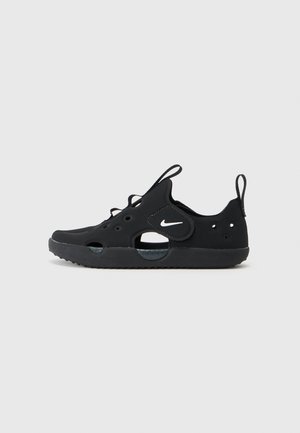 Tênis Nike pretos feitos de material sintético texturizado apresentam um formato arredondado, seções recortadas, cadarços e um pequeno logotipo na lateral.