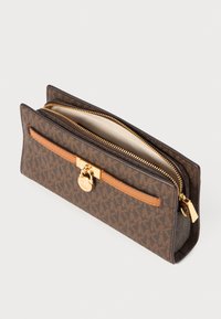 Brown patterned wallet with a gold zipper, a leather strap, and a gold hardware accent. Interior is cream-colored, showcasing stitching details.