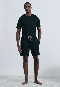 Μαύρο t-shirt με κοντά μανίκια και μαύρο σορτς με κορδόνι στη μέση. Απλός σχεδιασμός, ελαφρύ ύφασμα και άνετη εφαρμογή.