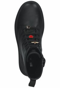 Bottine en cuir noir avec des lacets plats, trois charmes décoratifs (cœur rouge, étoile argentée, croix dorée) sur les lacets, semelle texturée.