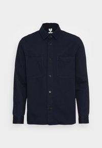 Chemise bleu marine à boutons en tissu lisse, dotée d'un col classique, de deux poches poitrine et de manches longues avec poignets boutonnés.