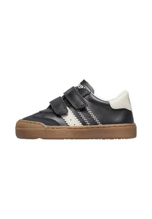 Sneaker in pelle nera con dettagli bianchi, strap in Velcro e suola in gomma color tan, caratterizzato da un design zigzag cucito lungo i lati.