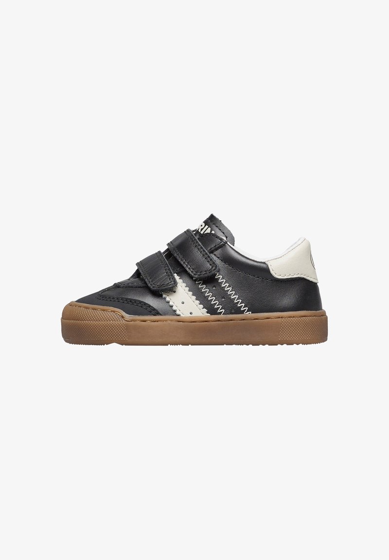 Sneaker in pelle nera con dettagli bianchi, strap in Velcro e suola in gomma color tan, caratterizzato da un design zigzag cucito lungo i lati.