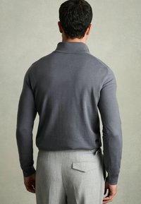 Grauer Langarmpullover mit Kragen, aus weichem Stoff, getragen mit hellgrauen maßgeschneiderten Hosen. Verfügt über ein minimalistisches Design und eine glatte Textur.