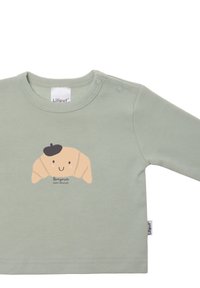 Hellgrünes Langarmshirt für Kleinkinder mit einem Croissant-Graphic und dem Text "Bonjour mon amour". Mit Druckknopfverschlüssen an der Schulter.