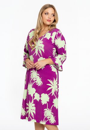 Lila Kleid mit floralen Muster in hellgrün, Dreiviertelärmel und V-Ausschnitt, aus einem weichen, fließenden Material gefertigt.