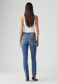 Mörkblå denimjeans med hög midja, femficksdesign och en logotyppatch på baksidan. Slät textur och lätt stretch i tyget.