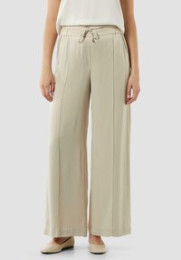 Beige broek met wijde pijpen, voorzien van een elastische tailleband en trekkoord, met zijzakken en een gladde, lichtgewicht stof.