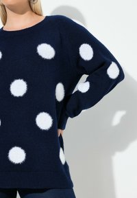 Námořnický svetr s velkými bílými nadýchanými puntíky, kulatým výstřihem a dlouhými rukávy. Texturovaná pletenina s žebrovaným lemem.