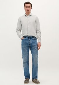 Lys grå skjorte med knapper, blå denimjeans og grå sko. Skjorten har et enkelt design, og jeansene har en klassisk pasform.