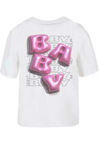 Hvid t-shirt med korte ærmer, der har store, blanke pink "BABY" bogstaver mod en sort tekstbaggrund med gentagne sætninger.