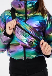 Iriserende synthetische pufferjack met een hoge kraag en ritszakken. De heuptas is diagonaal bevestigd en heeft een zwarte rits.