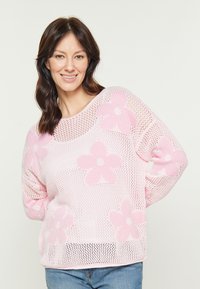 Maglione a rete rosa chiaro con grandi motivi floreali, colletto rotondo e vestibilità comoda. Accentuato da fiori di un rosa leggermente più scuro.