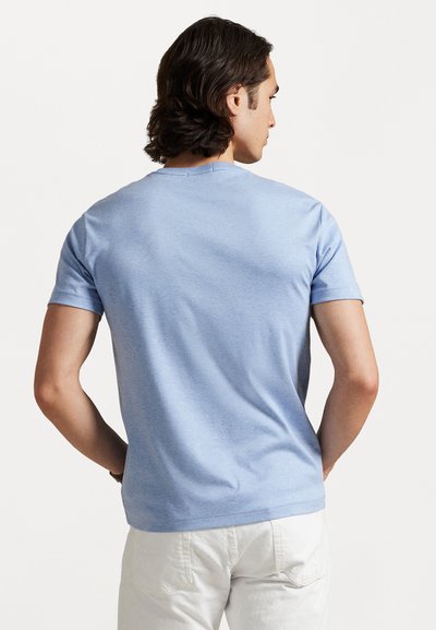 Gaiši zils kokvilnas T-krekls ar apaļu kakla izgriezumu un īsām piedurknēm, ar gludu tekstūru un brīvāka piegriezuma. Attēlots aizmugurējais skats.