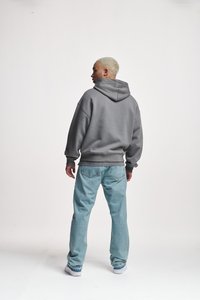 Graue Kapuzen-Sweatshirt mit einem lässigen Schnitt, gerippten Bündchen und einer Kängurutasche, kombiniert mit hellblauen, geraden Jeans. Rückansicht.