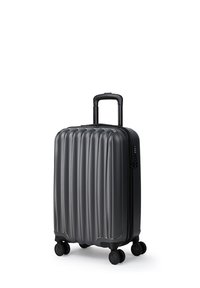 Twarda czarna walizka podróżna z pionowymi żłobieniami, czterema obrotowymi kółkami i wysuniętą teleskopową rączką.